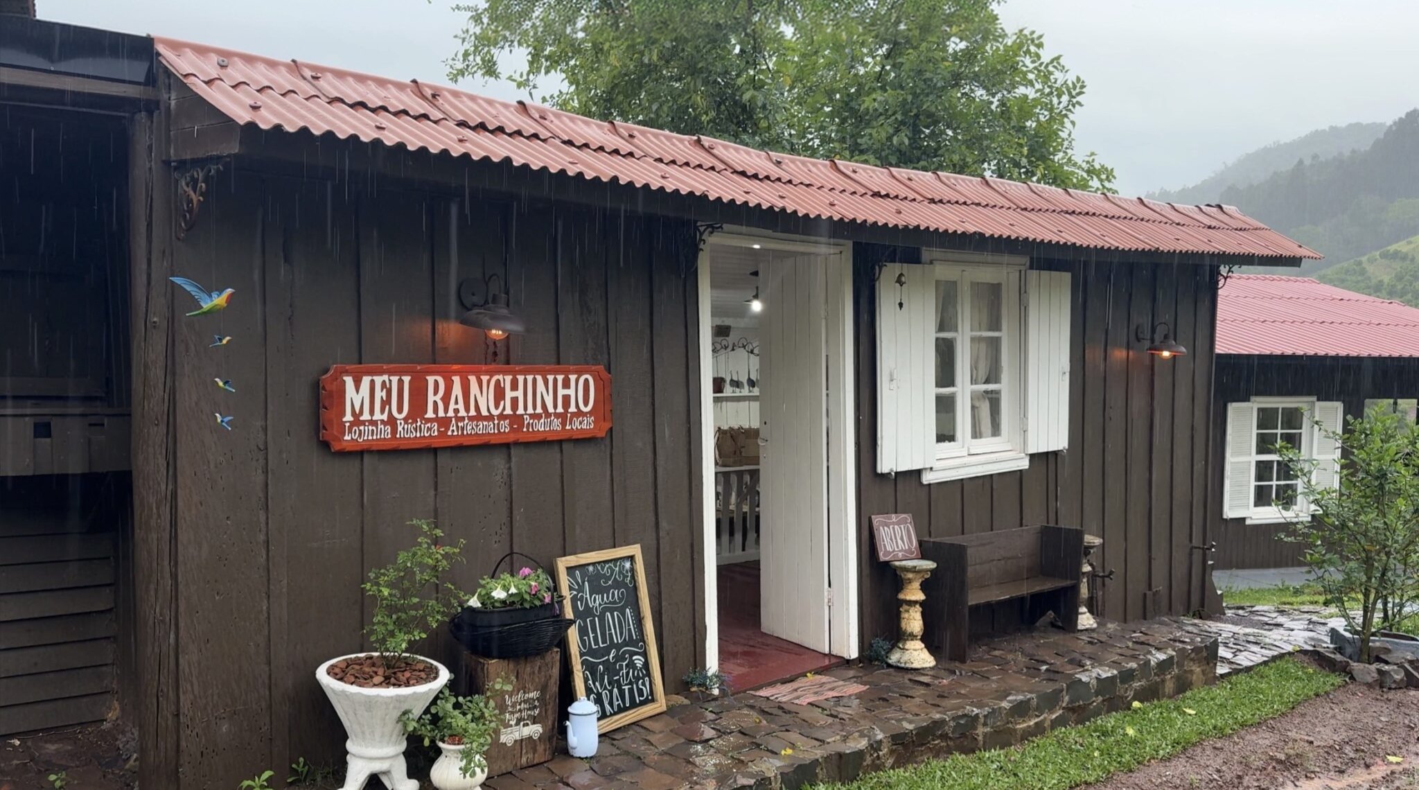 Fachada da lojinha Meu Ranchinho, com vasos de plantas e lousa na entrada